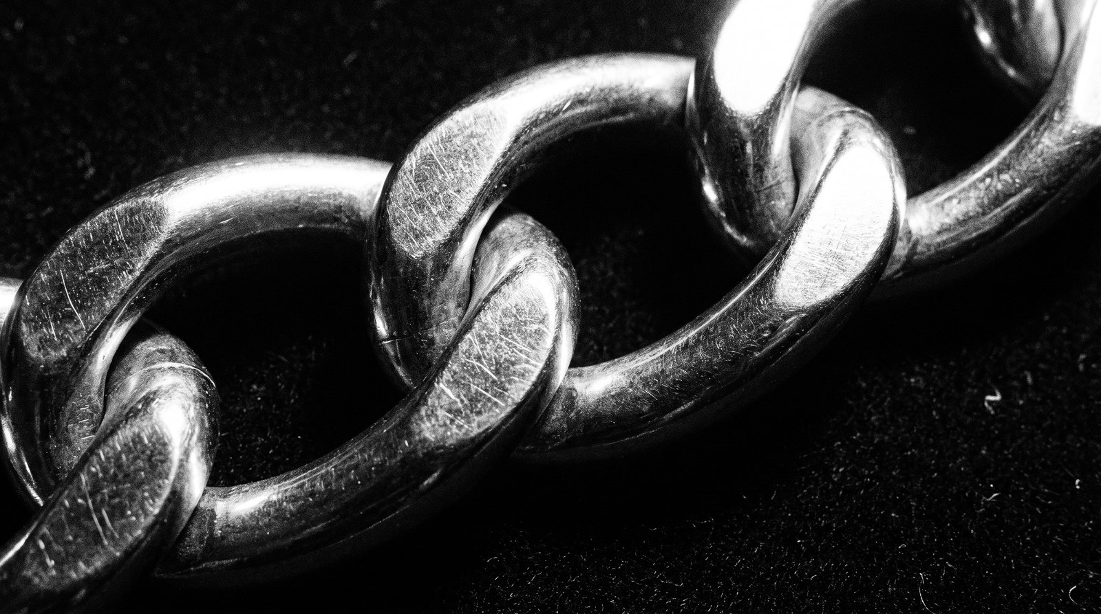 A macro shot of heavy interlocking steel chain links on black